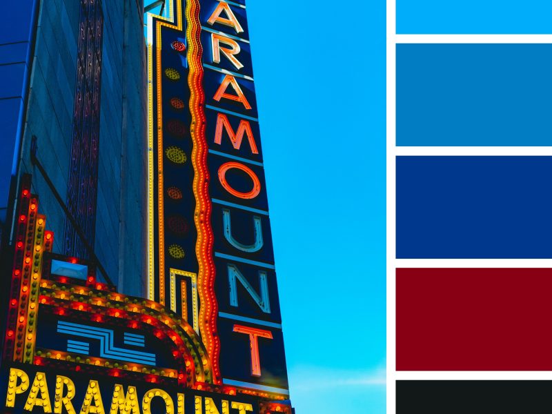 A grand vertical sign, emblazoned with bright yellow and red lights, stands prominently against a deep blue sky that transitions to near black